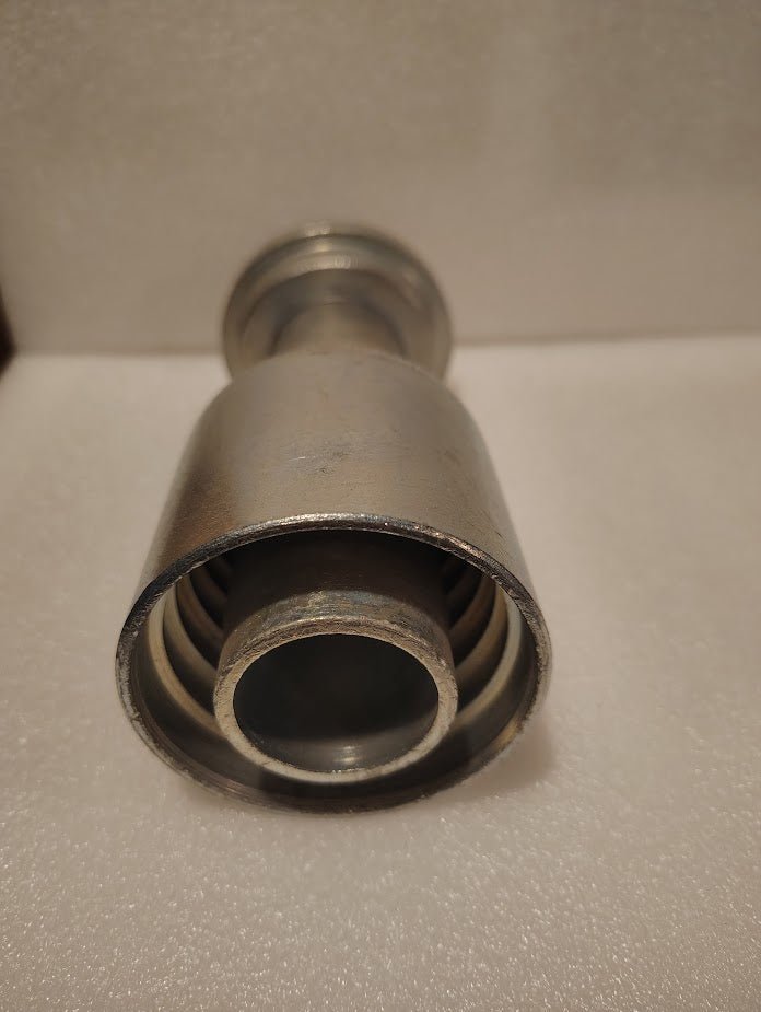 A close-up of a 43024U-G32 | 1 1/2 Hose x 2 Code 61 Flange Fitting - Straight (GW47-24x32), a metal cylindrical industrial part with concentric rings, shown on a white textured surface.