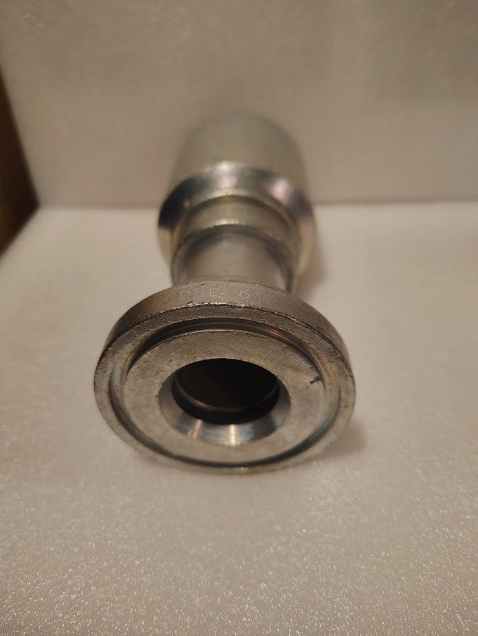 Close-up of a 43024U-G32 | 1 1/2 Hose x 2 Code 61 Flange Fitting - Straight (GW47-24x32) on a white textured surface, viewed from the open end facing the camera.