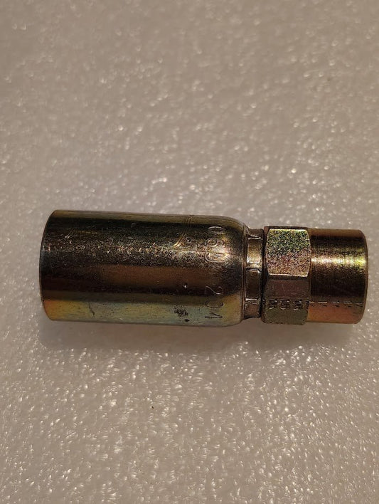 The Weatherhead 06U-204 fitting, a metallic hydraulic hose adapter with a threaded end, lies horizontally on a textured white surface. Its cylindrical design is compatible with 100R1 hoses for secure connections.