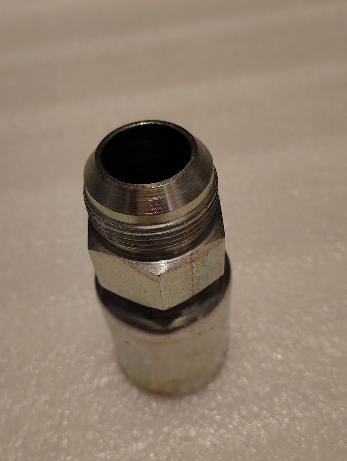 On a textured white background, a Weatherhead 20U-520 1 1/4 Hose x 1 1/4 JIC Male Fitting is partially unscrewed, showcasing its shiny finish that suggests craftsmanship from steel or a similar material.