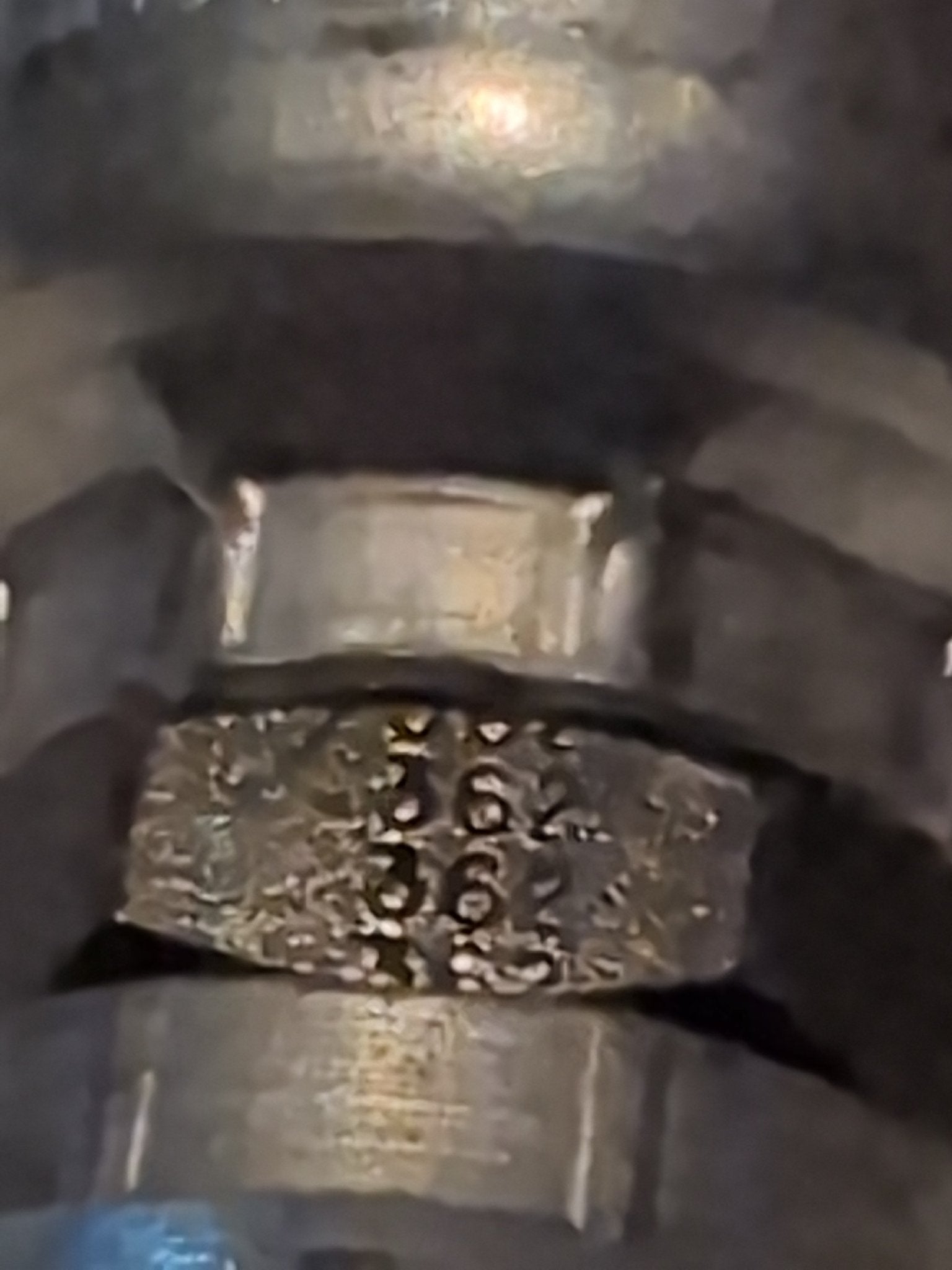 Close-up shot of metallic pipe structures engraved with 562 and 362, resembling rugged hydraulic hose setups. The weathered metal has a slightly reflective finish, likely featuring 12U-362 Weatherhead 3/4 Hose x 3/4 BSPP Female Fitting - Straight Swivel for 100R1 compatibility.