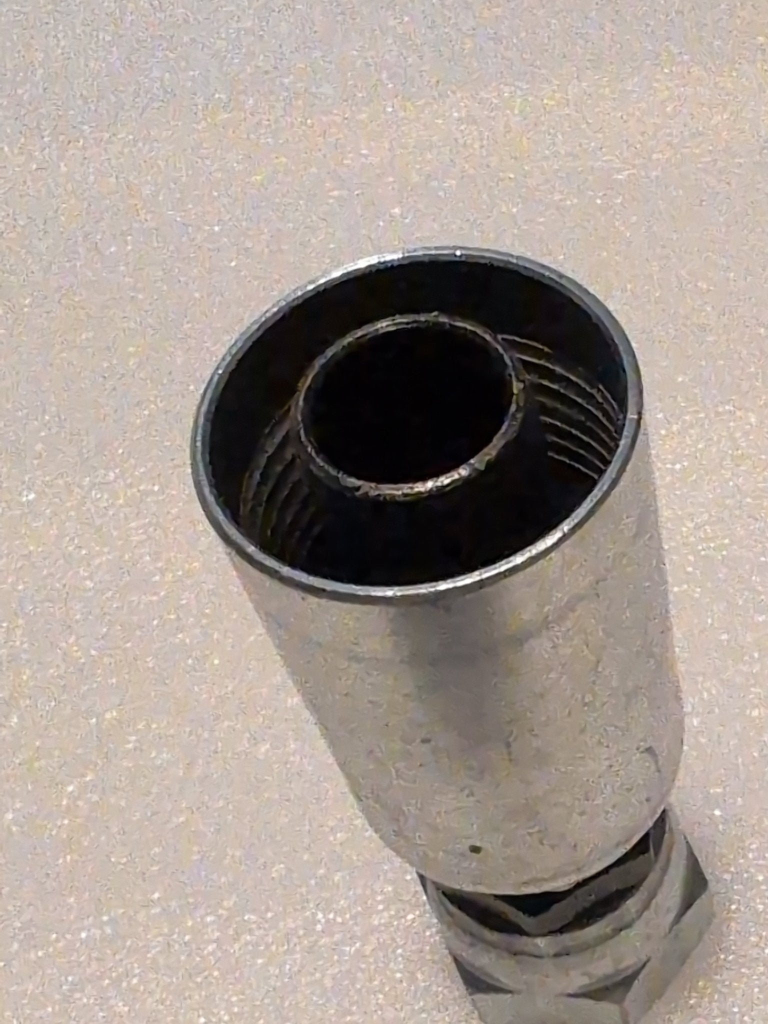 Close-up of a Weatherhead 12U-362 fitting, a straight swivel with a cylindrical shape and visible internal threads, compatible with 3/4 BSPP hoses, resting on a textured white surface.