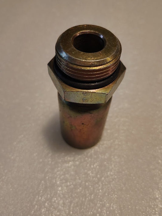 The 12U-P16 Weatherhead 3/4 Hose x 3/8 ORB Male Fitting, straight solid with a hexagonal nut and threaded end, stands upright on a smooth white surface, exhibiting a brass-like appearance with a slightly worn finish.