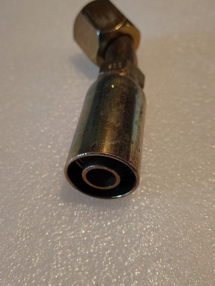 A close-up shows a 10U-692 Weatherhead 5/8 Hose x 3/4 JIC/SAE Female Fitting - 45 Swivel, featuring a hexagonal nut on textured white. This cylindrical fitting has visible threading and a reflective finish, compatible with Weatherhead fittings.