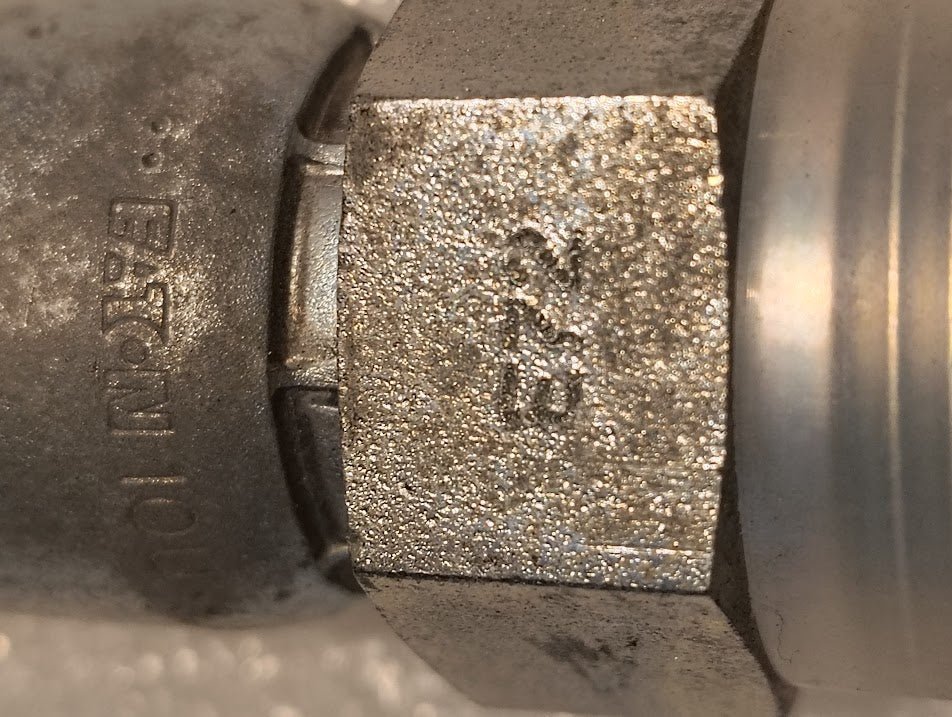 A close-up of the EATON engraved Weatherhead 10U-E72 fitting showcases a textured hexagonal nut with minor scratches and a metallic sheen. This durable, straight solid 5/8 hose x 3/4 ORF male fitting is compatible with 100R1 hydraulic hoses.