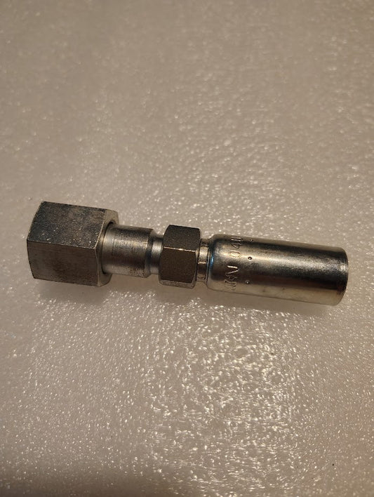 The Weatherhead 04U-S68, a metal coupling connector, sits on a textured beige surface, featuring a hexagonal and cylindrical end joined by a middle section. This metallic and shiny tool evokes an industrial look akin to hydraulic hose fittings.