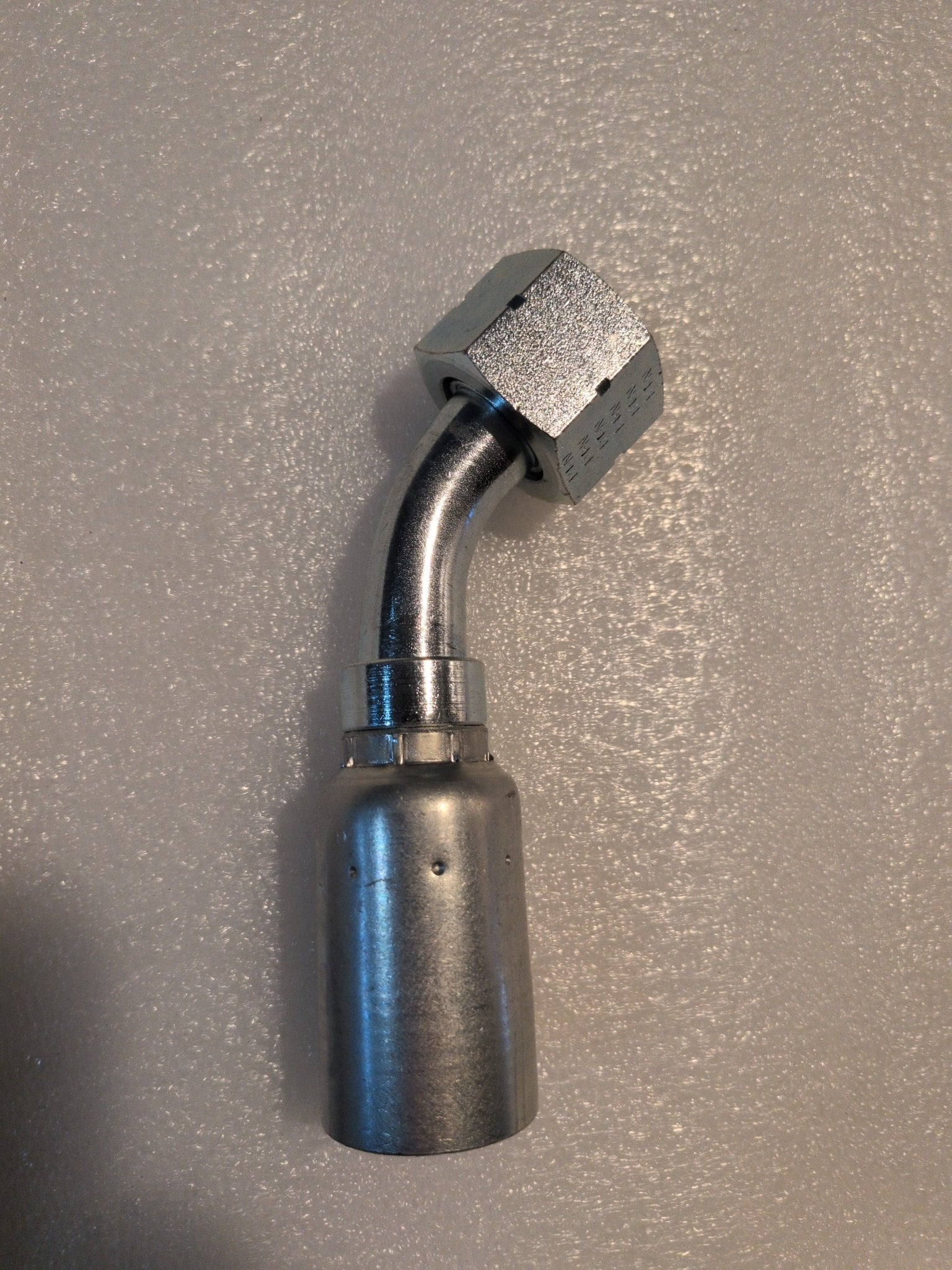 The 12U-L72 Weatherhead fitting, a 3/4 hose with a 45-degree swivel and hexagonal connector, lies gracefully on a textured white surface.