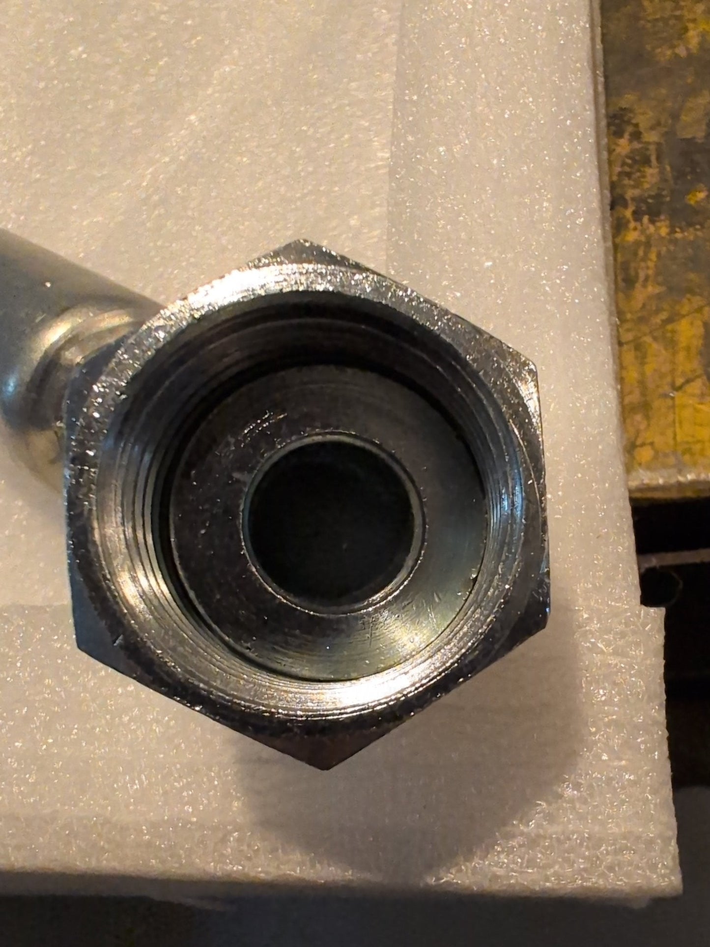 Close-up of the Weatherhead 3/4 Hose x 3/4 ORF Female Fitting - 45 Swivel on textured white foam. Compatible with 100R series hydraulic hose fittings, it has a threaded interior and its shiny surface reflects light from above.