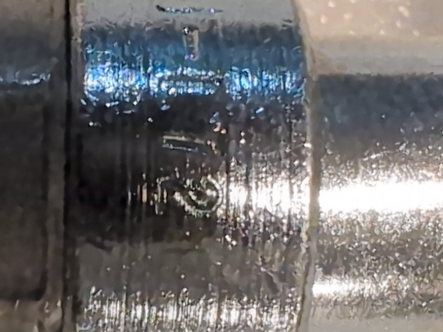 Close-up image of a shiny, metallic cylindrical object resembling a Weatherhead 12U-L72 fitting with engraved text 3. The surface is slightly reflective and textured.