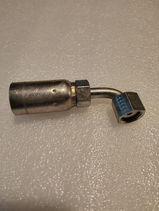 A Weatherhead 06U-A24 metal hydraulic fitting with a cylindrical body and a bent elbow shape lies on a textured surface, featuring a hexagonal nut at one end and a threaded connector at the other, showcasing interchangeable fitting precision.
