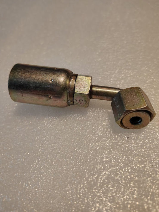 The 08U-A26 Weatherhead fitting, featuring a straight metal body with a hexagonal nut on one end and a larger cylindrical section on the other, commonly used with Weatherhead fittings, rests on a textured, light-colored surface.