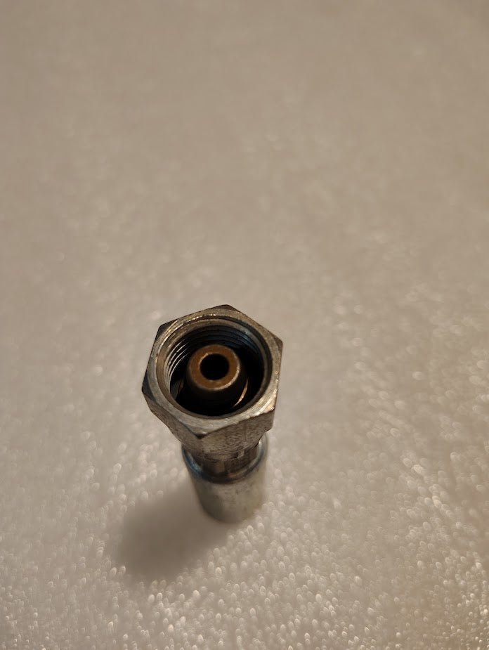 Close-up of a metallic Weatherhead 04U-58C fitting against a light, textured background. The fitting has a central circular opening with threaded edges, similar to those used with 100R2 hoses.