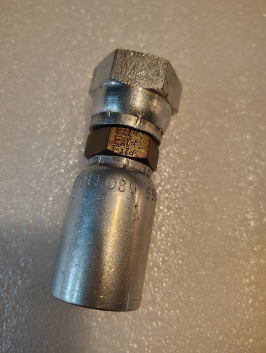 Close-up of a metallic Weatherhead 08U-66C fitting with hexagonal sections and engraved details, compatible with 100R1 hoses, positioned on a textured white surface.