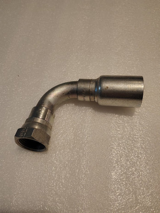 A close-up of the 16U-86P Weatherhead fitting, 90-degree swivel design for 1 hose with one threaded BSPP female end and one smooth end, rests on a textured white surface.