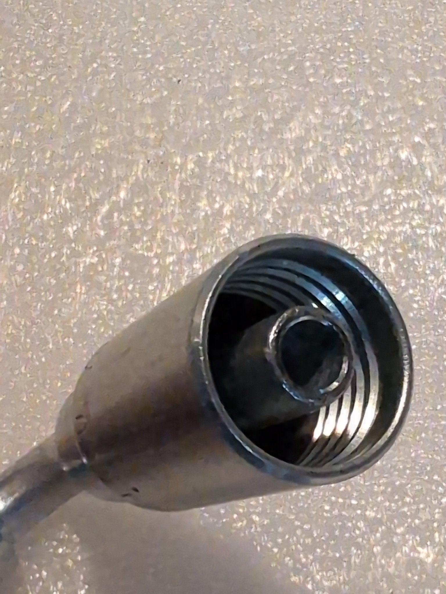 Close-up of a 06U-76P Weatherhead fitting with visible internal threads, compatible with 3/8 hose and designed for 3/8 BSPP connections. The reflective metal surface emphasizes its cylindrical shape against a textured light background.